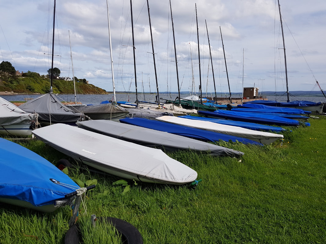 Smaller dinghies stored on the grass in the dinghy park at Chanonry Sailing Club