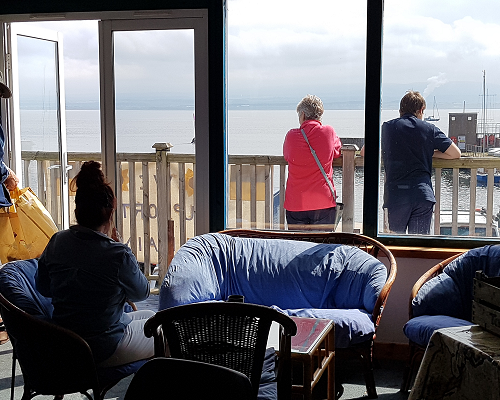 Chanonry Sailing Club member looking out to the balcony where two members are watching activities.