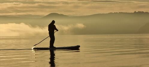 Lone SUP paddler outlined at sunset at Fortrose